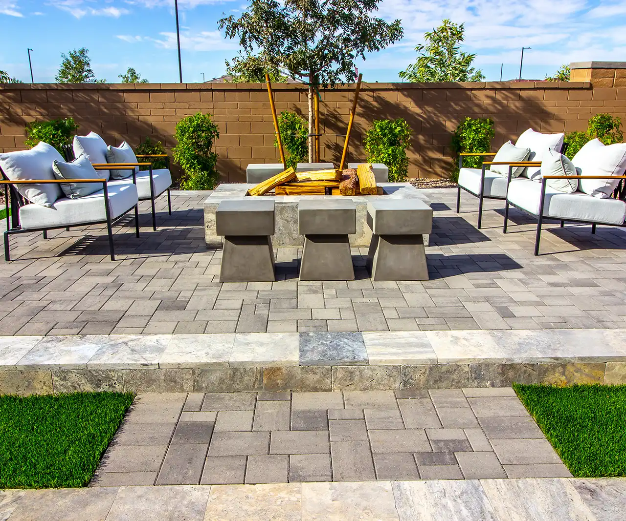 Backyard paver patio with fire pit seating and artificial turf accents