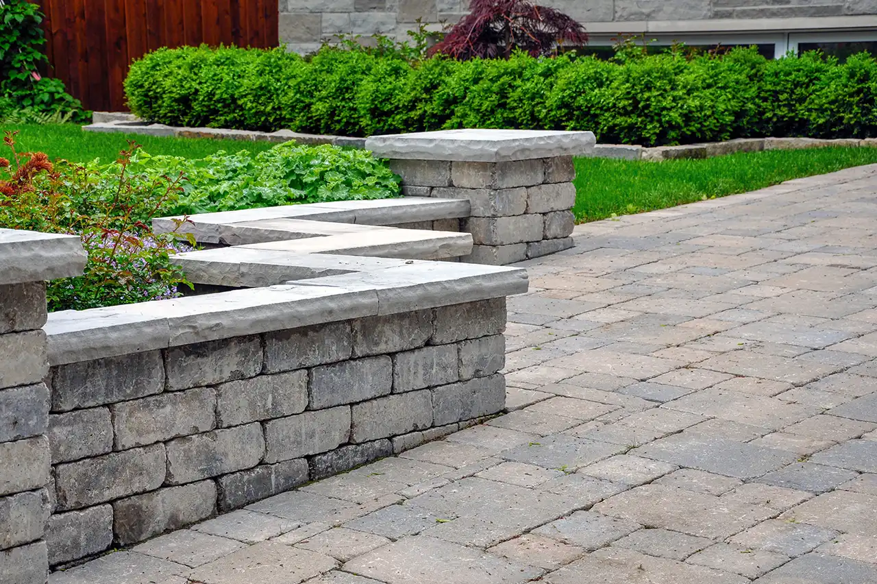 Stone seating wall and paver patio with landscaped yard
