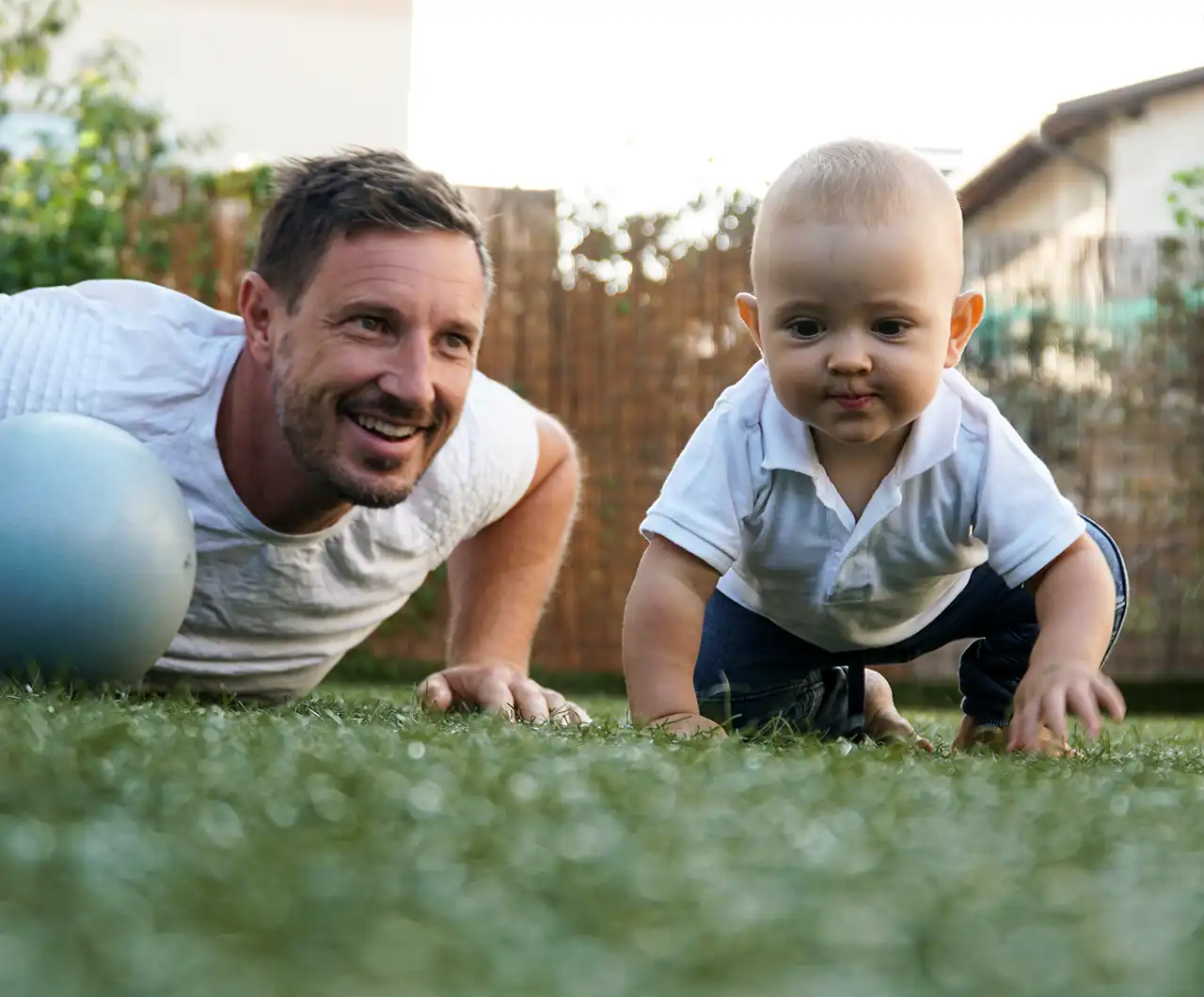 Father and young child enjoying time together on an artificial turf lawn