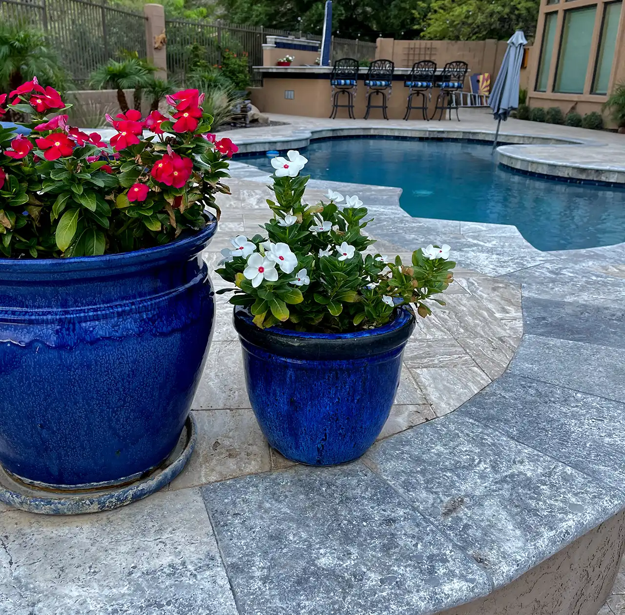 Travertine pool deck with natural stone detailing and colorful planters